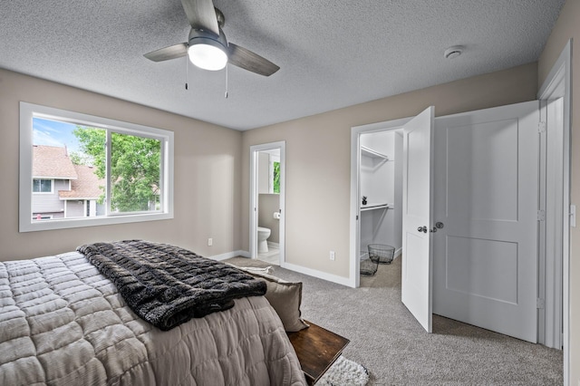 3825 122nd Ave NW, Coon Rapids, MN 55433 - carpeted bedroom with a textured ceiling, connected bathroom, a spacious closet, ceiling fan, and baseboards