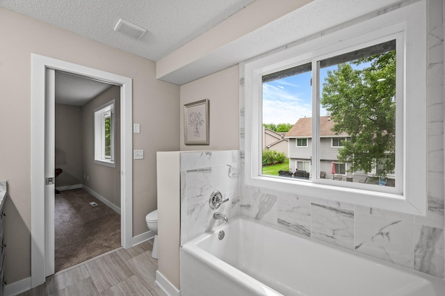 3825 122nd Ave NW, Coon Rapids, MN 55433 - full bath with healthy amount of natural light, a garden tub, toilet, baseboards, and a textured ceiling