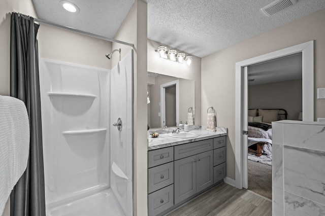 3825 122nd Ave NW, Coon Rapids, MN 55433 - ensuite bathroom featuring wood finished floors, vanity, a shower with shower curtain, and a textured ceiling
