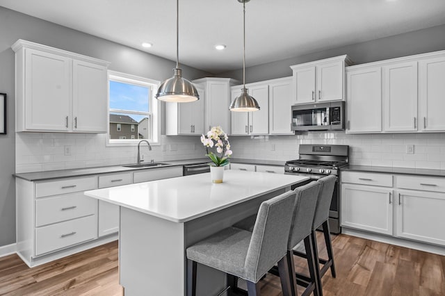 9842 51st St NE, Saint Michael, MN 55376 - kitchen with appliances with stainless steel finishes, a sink, a kitchen breakfast bar, recessed lighting, and wood finished floors