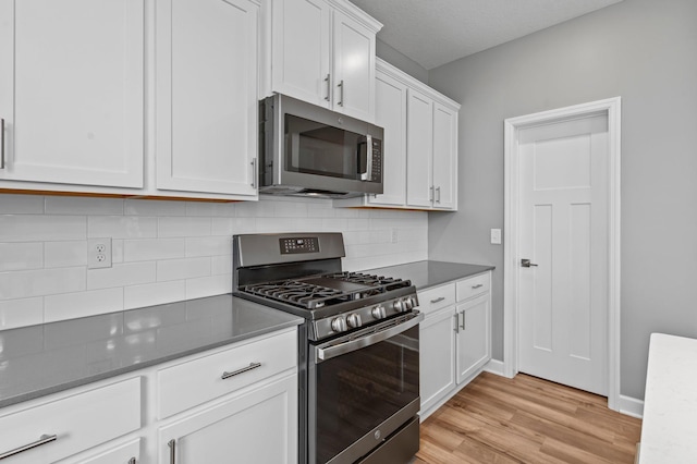 9842 51st St NE, Saint Michael, MN 55376 - kitchen with stainless steel appliances, light wood-style floors, white cabinets, backsplash, and baseboards