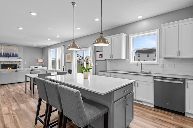 9842 51st St NE, Saint Michael, MN 55376 - kitchen with dishwashing machine, a sink, backsplash, a center island, and light wood-style floors