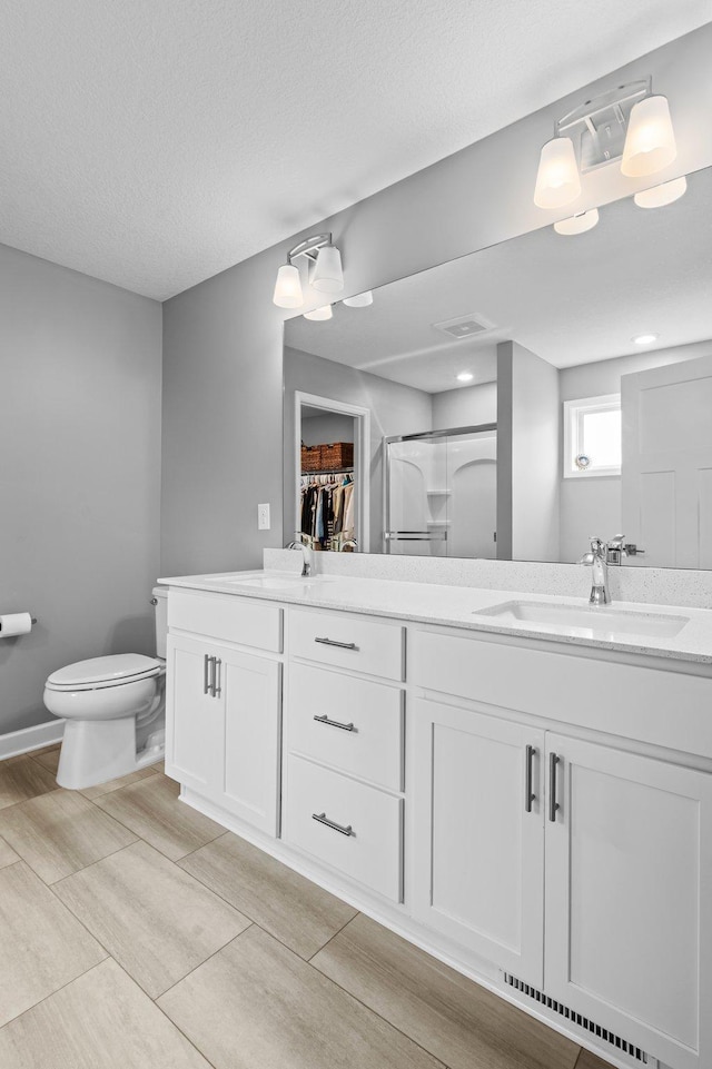 9842 51st St NE, Saint Michael, MN 55376 - bathroom featuring double vanity, toilet, a stall shower, and a spacious closet