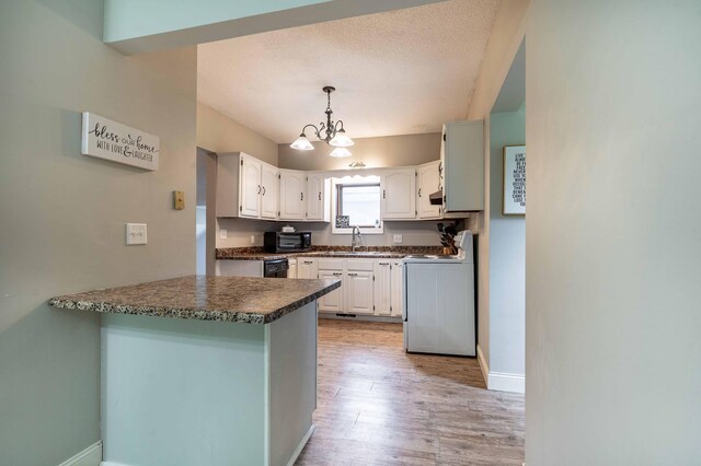113 7th Ave SE, Elbow Lake, MN 56531 - kitchen with white range oven, a peninsula, dark countertops, a chandelier, and a sink