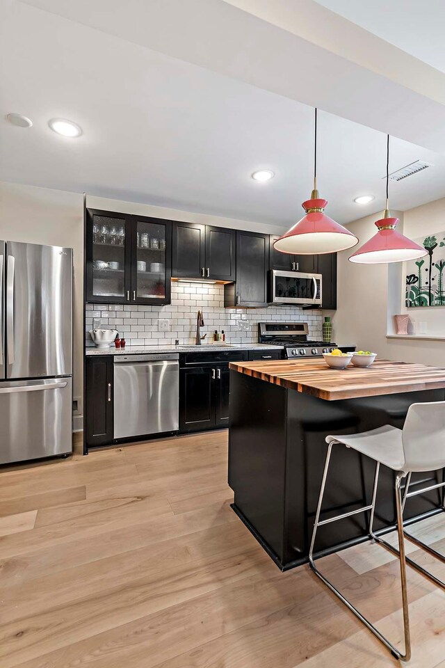 75 Oregon Ave S, Golden Valley, MN 55426 - kitchen featuring stainless steel appliances, dark cabinetry, a sink, butcher block counters, and a kitchen breakfast bar