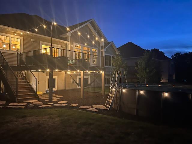 227 Maple Ln, Jordan, MN 55352 - back of house at night with stairs, a wooden deck, and an outdoor pool