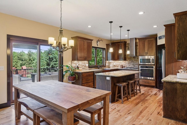 227 Maple Ln, Jordan, MN 55352 - kitchen with stainless steel appliances, wall chimney range hood, a kitchen island, tasteful backsplash, and recessed lighting