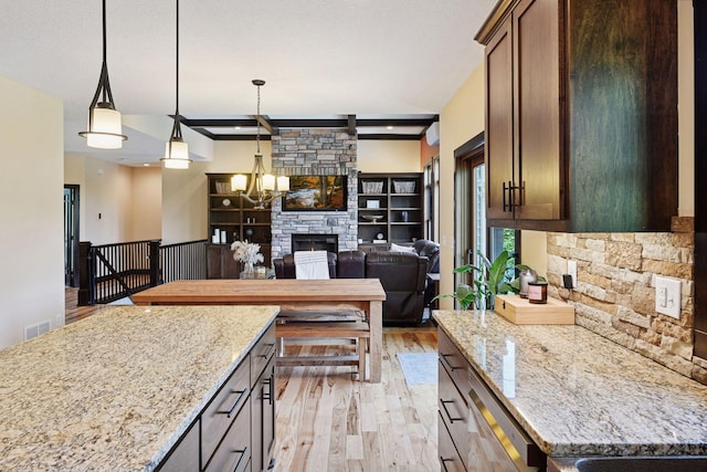 227 Maple Ln, Jordan, MN 55352 - kitchen with light wood finished floors, light stone counters, pendant lighting, open floor plan, and a fireplace