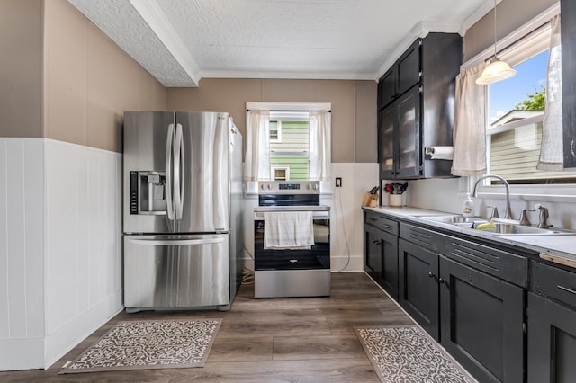 473 4th St, Winona, MN 55987 - kitchen featuring appliances with stainless steel finishes, a sink, ornamental molding, a textured ceiling, and dark wood finished floors