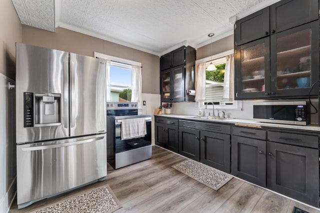 473 4th St, Winona, MN 55987 - kitchen with appliances with stainless steel finishes, a sink, light countertops, light wood-type flooring, and decorative light fixtures