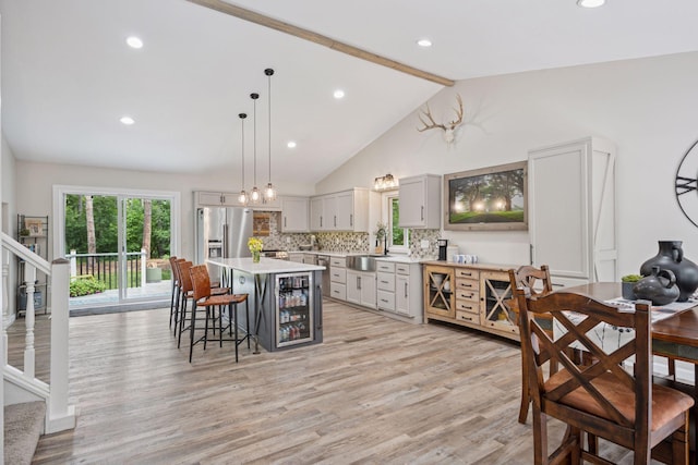 13171 Island View Dr NW, Elk River, MN 55330 - kitchen with stainless steel refrigerator with ice dispenser, light countertops, a kitchen bar, beam ceiling, and light wood-type flooring