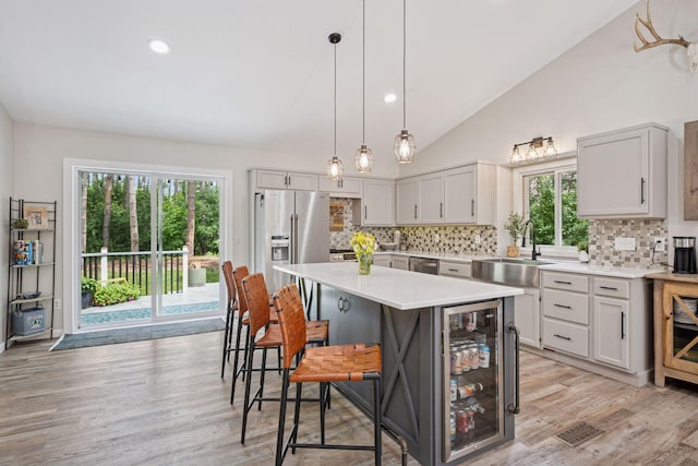 13171 Island View Dr NW, Elk River, MN 55330 - kitchen featuring wine cooler, appliances with stainless steel finishes, decorative backsplash, a breakfast bar, and light countertops