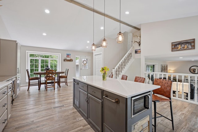 13171 Island View Dr NW, Elk River, MN 55330 - kitchen with stainless steel microwave, a kitchen bar, light countertops, light wood-type flooring, and recessed lighting