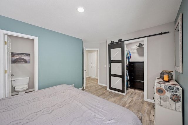13171 Island View Dr NW, Elk River, MN 55330 - bedroom with a barn door, light wood-style floors, a spacious closet, a closet, and ensuite bathroom