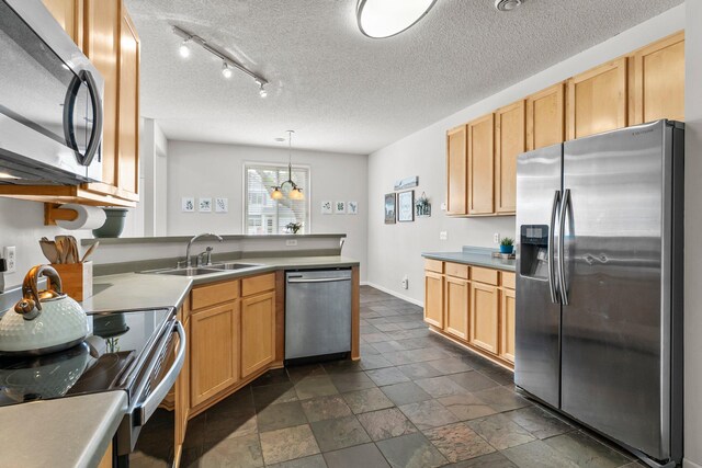 13055 Europa Trail Way N Unit A, Hugo, MN 55038 - kitchen featuring appliances with stainless steel finishes, a sink, a peninsula, a textured ceiling, and baseboards