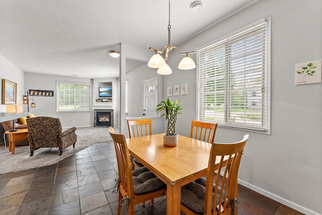 13055 Europa Trail Way N Unit A, Hugo, MN 55038 - dining area with a textured ceiling, baseboards, stone tile floors, and a glass covered fireplace