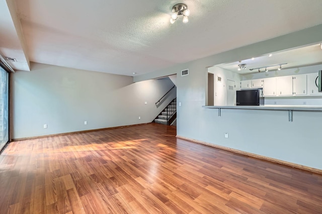 8932 Neill Lake Rd Unit 112B, Eden Prairie, MN 55347 - unfurnished living room with light wood-style floors, stairs, baseboards, and a textured ceiling