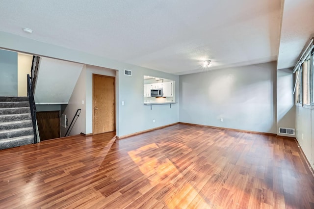 8932 Neill Lake Rd Unit 112B, Eden Prairie, MN 55347 - unfurnished living room with wood finished floors, a textured ceiling, stairs, and baseboards