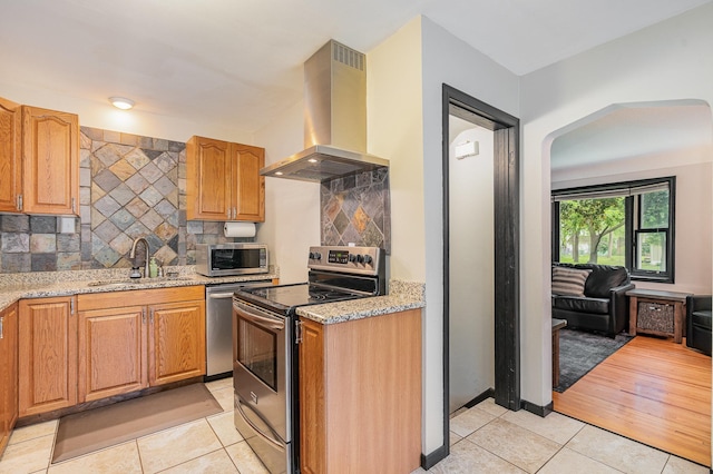 4101 Welcome Ave N, Robbinsdale, MN 55422 - kitchen featuring stainless steel appliances, island range hood, light tile patterned floors, light stone counters, and backsplash