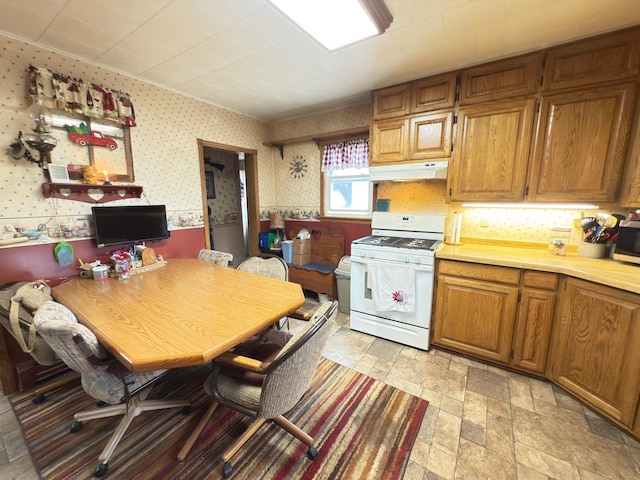 107 3rd Ave, Bellingham, MN 56212 - kitchen with white range with gas cooktop, under cabinet range hood, wallpapered walls, light countertops, and light stone finish flooring