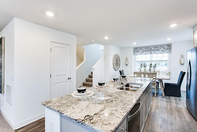 12549 Guadalcanal Cir NE Unit E, Blaine, MN 55449 - kitchen with stainless steel appliances, dark wood-style flooring, a sink, an island with sink, and light stone countertops