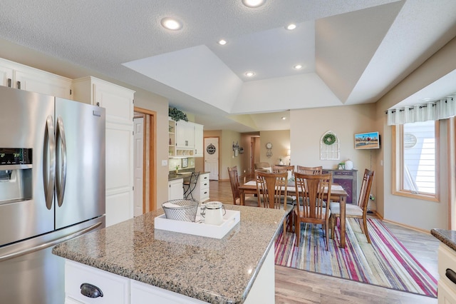 2301 170th Ln NW, Andover, MN 55304 - kitchen featuring stainless steel refrigerator with ice dispenser, light wood-style floors, white cabinets, light stone counters, and a kitchen island
