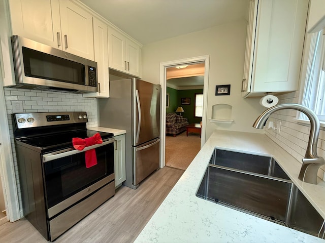 3243 Cleveland St NE, Minneapolis, MN 55418 - kitchen featuring stainless steel appliances, a sink, tasteful backsplash, light wood-style flooring, and white cabinetry