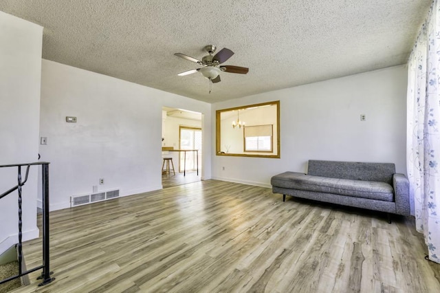 9705 99th Ave N, Maple Grove, MN 55369 - living area with wood finished floors, a ceiling fan, a textured ceiling, baseboards, and a chandelier