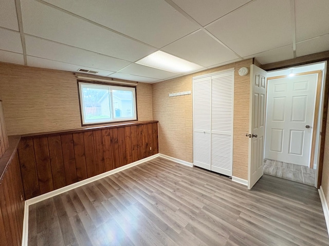 9705 99th Ave N, Maple Grove, MN 55369 - unfurnished bedroom with a drop ceiling, wood finished floors, baseboards, and wood walls