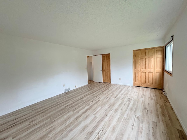 9705 99th Ave N, Maple Grove, MN 55369 - unfurnished bedroom featuring light wood-style floors, a textured ceiling, and baseboards