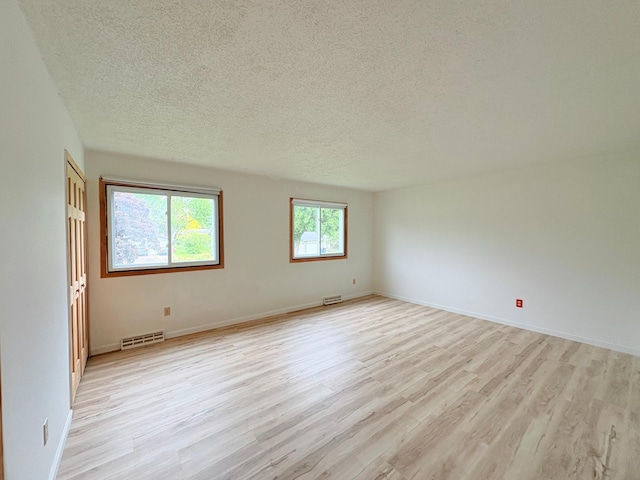 9705 99th Ave N, Maple Grove, MN 55369 - unfurnished room featuring light wood-style flooring, a textured ceiling, and baseboards
