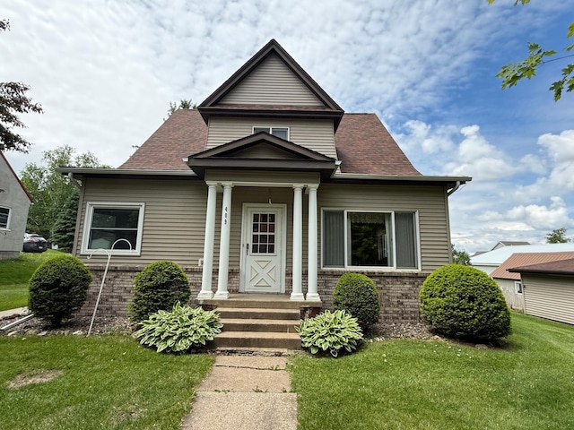 409 Maple St N, Mabel, MN 55954 - bungalow-style house featuring a front yard, brick siding, and a shingled roof