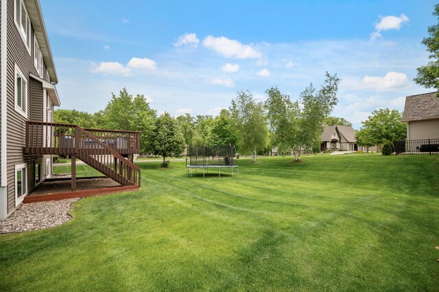 18301 100th Ave N, Osseo, MN 55311 - view of grassy yard featuring a trampoline, a deck, and stairs