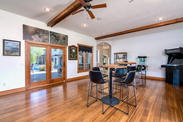 24534 474th Ln, Elysian Twp, MN 56028 - dining space featuring a textured ceiling, arched walkways, beamed ceiling, baseboards, and wood finished floors
