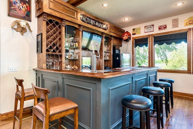 24534 474th Ln, Elysian Twp, MN 56028 - indoor dry bar featuring hardwood / wood-style floors, baseboards, freestanding refrigerator, recessed lighting, and a textured ceiling