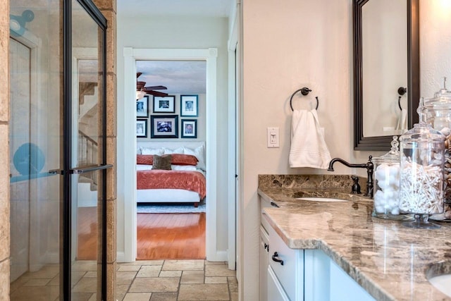 24534 474th Ln, Elysian Twp, MN 56028 - full bath with vanity, stone tile floors, ensuite bathroom, a ceiling fan, and a stall shower