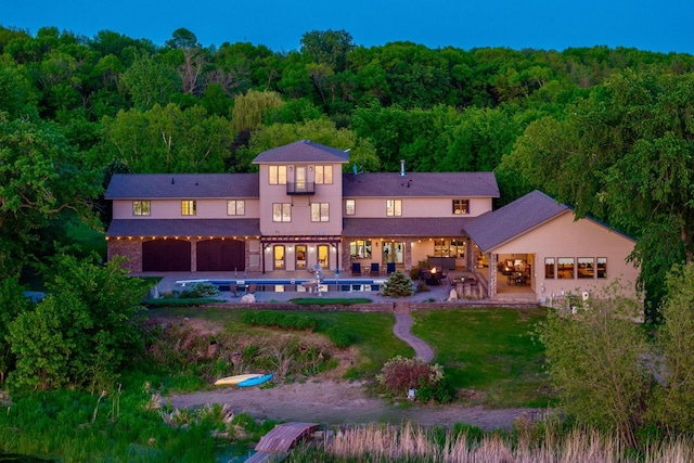 24534 474th Ln, Elysian Twp, MN 56028 - back of house with a forest view, an outdoor pool, a patio area, and a lawn