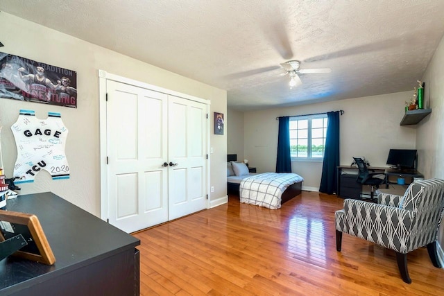 24534 474th Ln, Elysian Twp, MN 56028 - bedroom with an office area, light wood-style floors, a closet, a ceiling fan, and a textured ceiling