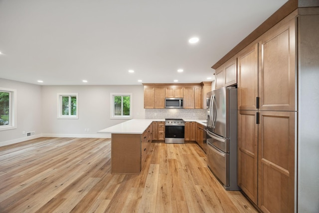 3936 Quail Ave N, Robbinsdale, MN 55422 - kitchen with appliances with stainless steel finishes, a peninsula, recessed lighting, light wood-style flooring, and light countertops