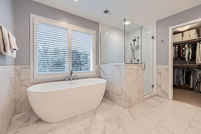 946 Wild Rose Ct, Eagan, MN 55123 - bathroom with marble finish floors, a soaking tub, tile walls, a stall shower, and a spacious closet