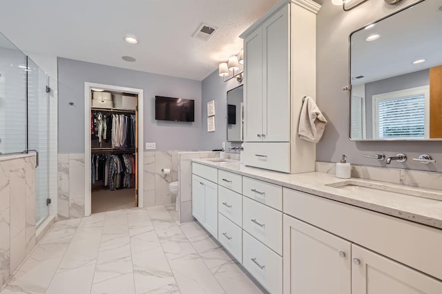 946 Wild Rose Ct, Eagan, MN 55123 - bathroom featuring double vanity, marble finish floors, a stall shower, tile walls, and a walk in closet