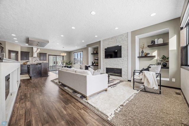 2800 Mcleod Dr E, West Fargo, ND 58078 - living room featuring a textured ceiling, a stone fireplace, recessed lighting, dark wood-style floors, and baseboards