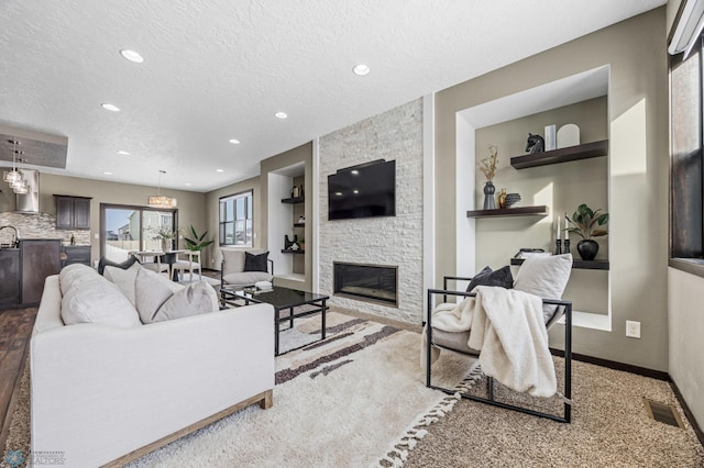 2800 Mcleod Dr E, West Fargo, ND 58078 - carpeted living area with a textured ceiling, a stone fireplace, recessed lighting, and baseboards