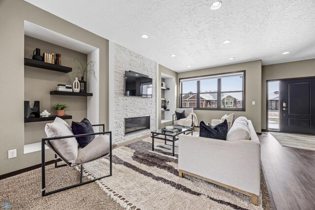2800 Mcleod Dr E, West Fargo, ND 58078 - living area featuring a textured ceiling, a stone fireplace, recessed lighting, baseboards, and wood finished floors