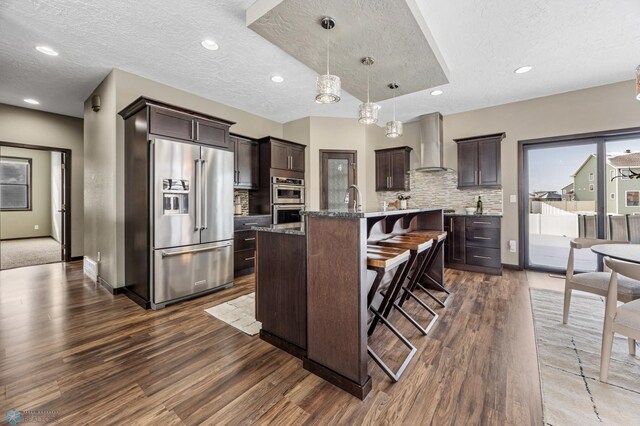 2800 Mcleod Dr E, West Fargo, ND 58078 - kitchen featuring appliances with stainless steel finishes, wall chimney range hood, dark wood finished floors, dark brown cabinetry, and a textured ceiling