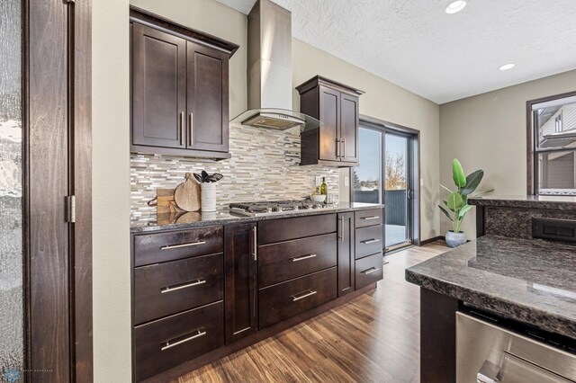 2800 Mcleod Dr E, West Fargo, ND 58078 - kitchen with wall chimney range hood, dark wood-style floors, dark stone counters, stainless steel gas stovetop, and recessed lighting