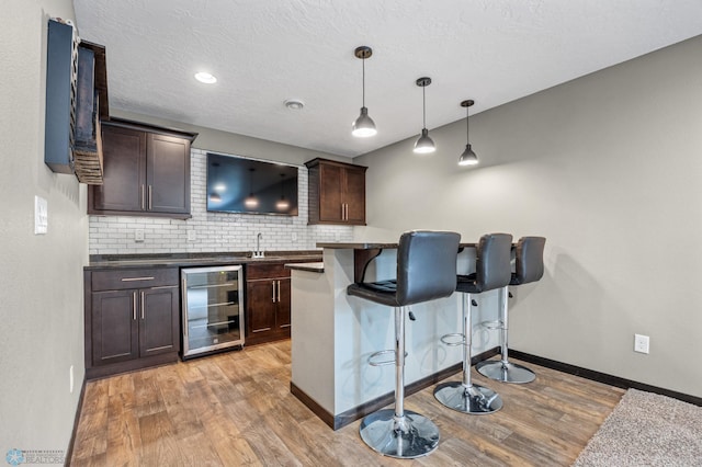 2800 Mcleod Dr E, West Fargo, ND 58078 - indoor wet bar featuring beverage cooler, light wood finished floors, backsplash, baseboards, and decorative light fixtures