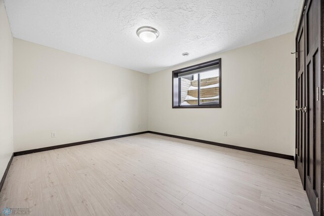 2800 Mcleod Dr E, West Fargo, ND 58078 - empty room featuring light wood-style flooring, baseboards, and a textured ceiling