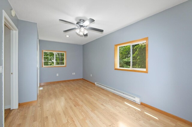 6198 210th Ave SE, Lake Lillian Twp, MN 56253 - unfurnished bedroom featuring a baseboard heating unit, multiple windows, light wood-style floors, and baseboards
