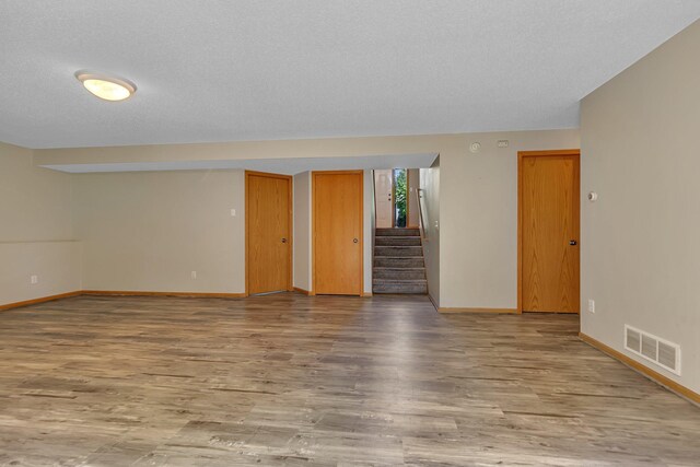 2821 15th Ave S, Saint Cloud, MN 56301 - empty room with wood finished floors, baseboards, stairway, and a textured ceiling
